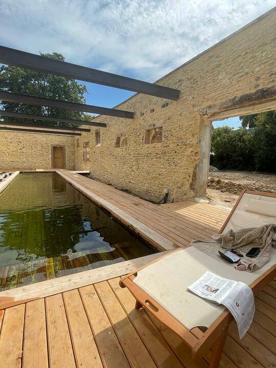 Piscine naturelle en bois immergé avec un volet immergé et une terrasse en bois à côté de Paris